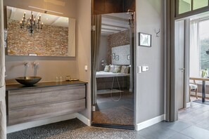 A modern bathroom with a large mirror, a wooden vanity, a glass shower enclosure, and a visible bedroom with a bed and a bathroom. - Boutique Hotel 't Vosje (Business & Leisure) (Haarlem)