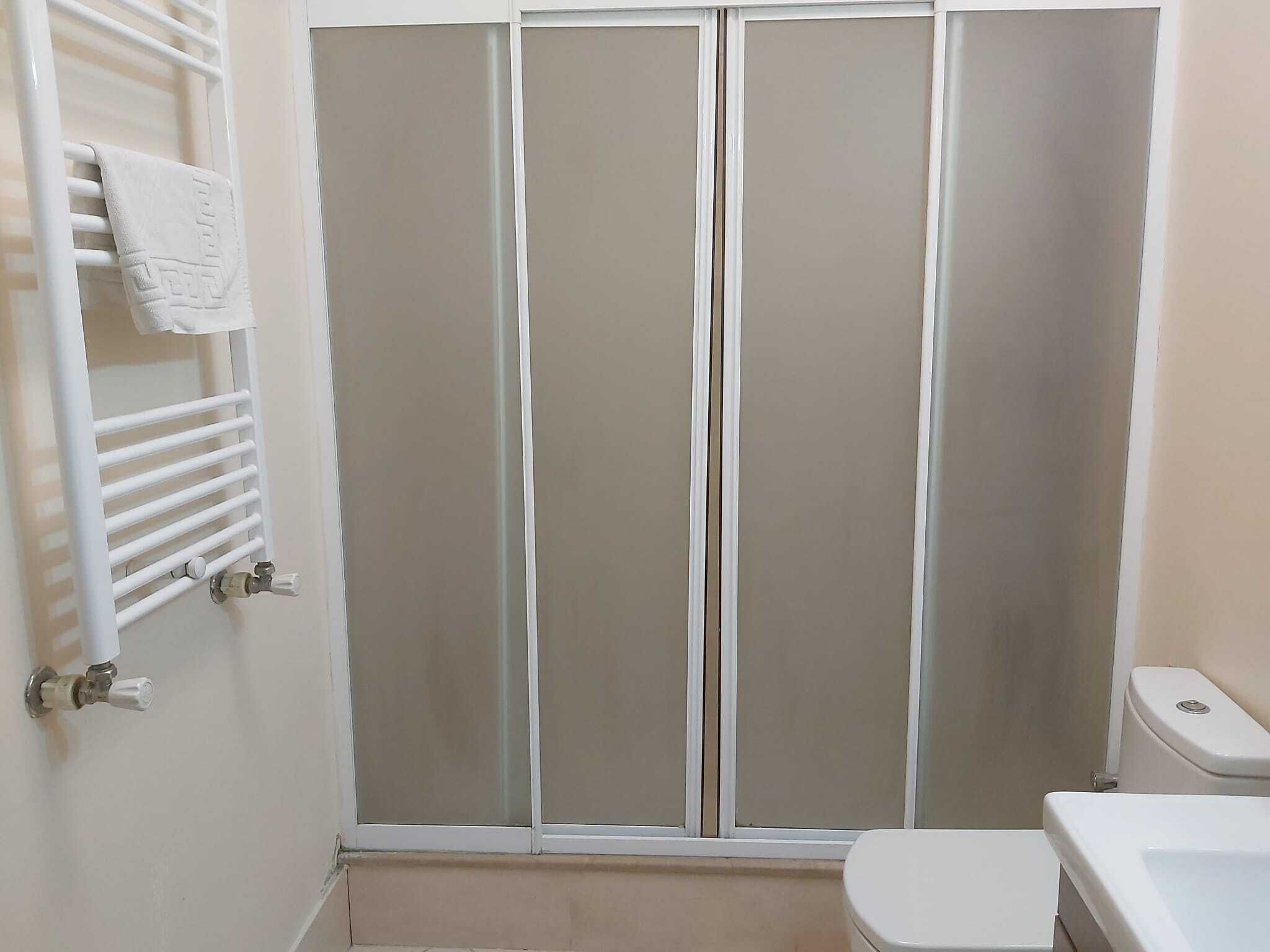 A bathroom with a toilet, a towel rack, and a shower enclosure.