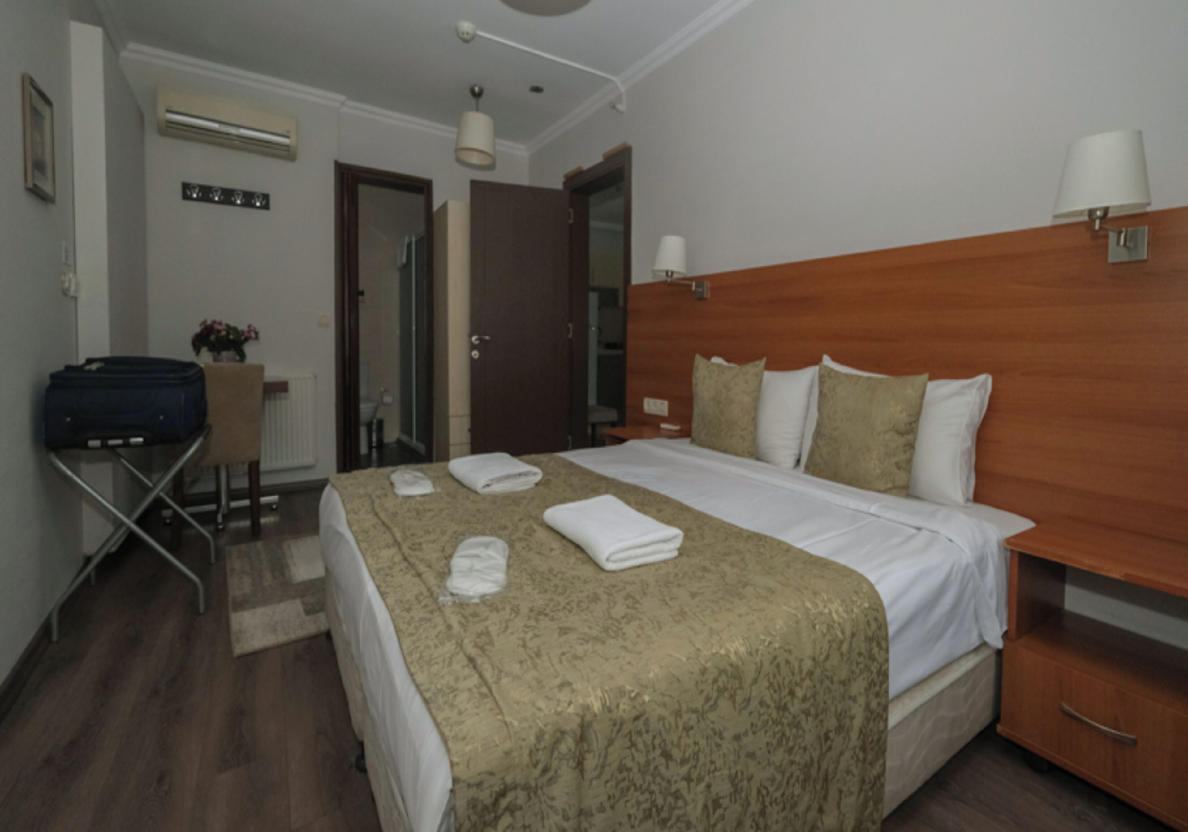 A hotel room with a bed, bedside tables, a desk, and a chair.