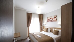 Una habitación de hotel con cama, mesita de noche, lámpara y una obra de arte en la pared.
