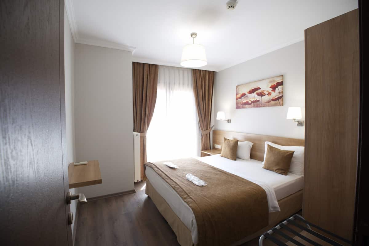 A hotel room with a bed, bedside table, lamp, and artwork on the wall.