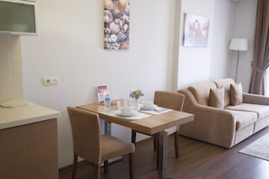A modern living room with a dining table, a sofa, and a TV.