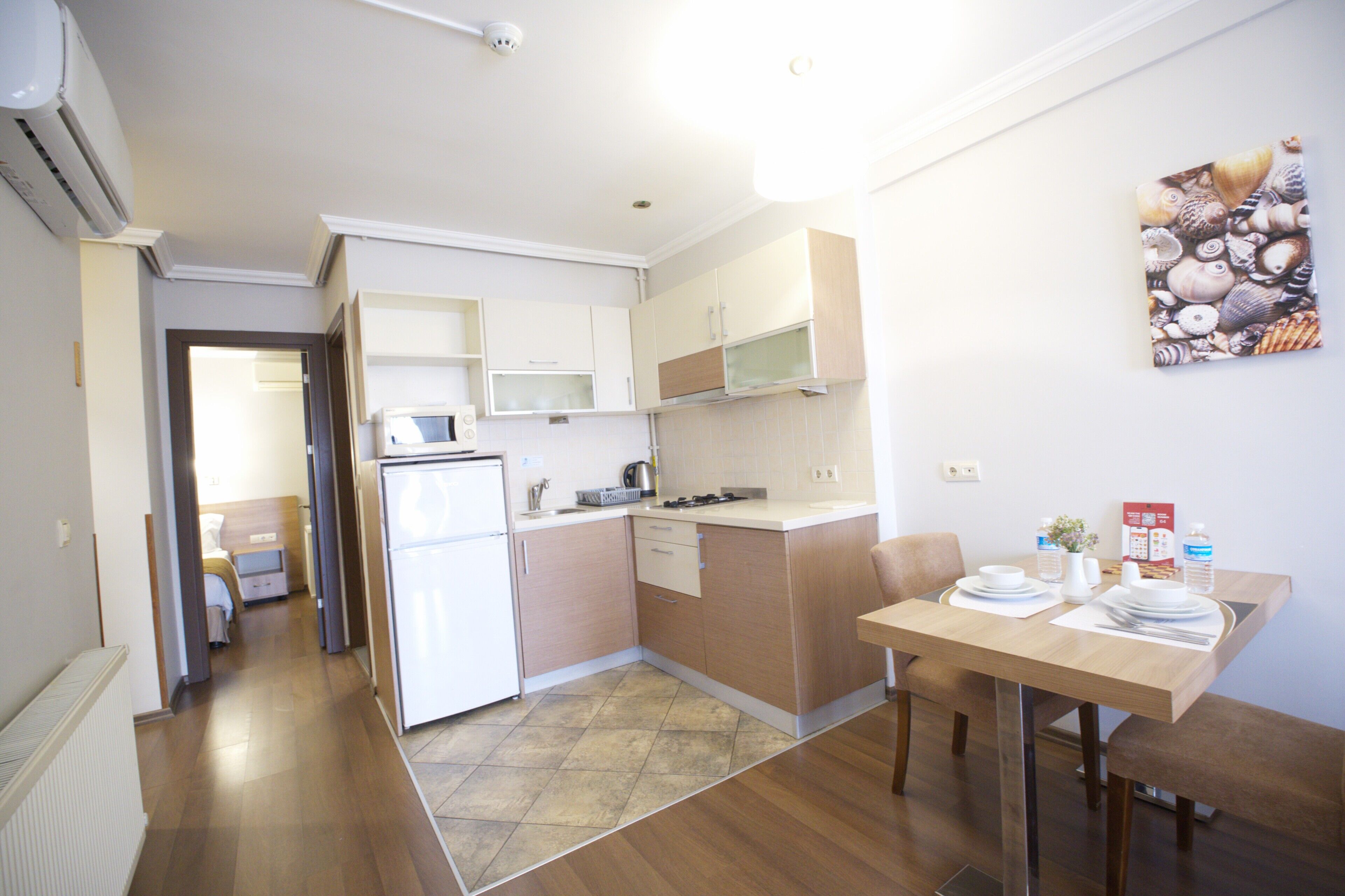 A compact kitchen with a refrigerator, microwave, and wooden cabinets.
