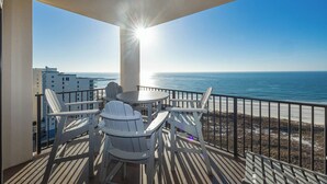 Un balcón con mesa y sillas, con vista a una playa y el océano.