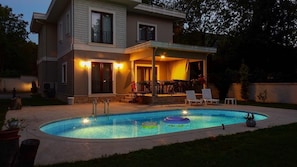 A two-story house with a swimming pool, a covered patio, and a deck.