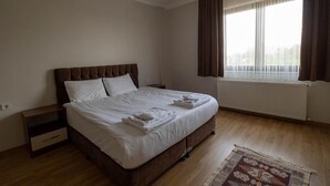 Un dormitorio con cama, mesita de noche, ventana con cortinas y radiador.