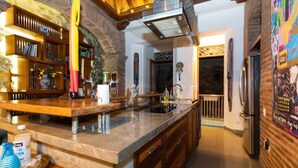 A kitchen with a large island, wooden cabinets, and a stainless steel refrigerator.