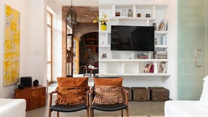 A living room with a TV, white shelves, and two chairs.