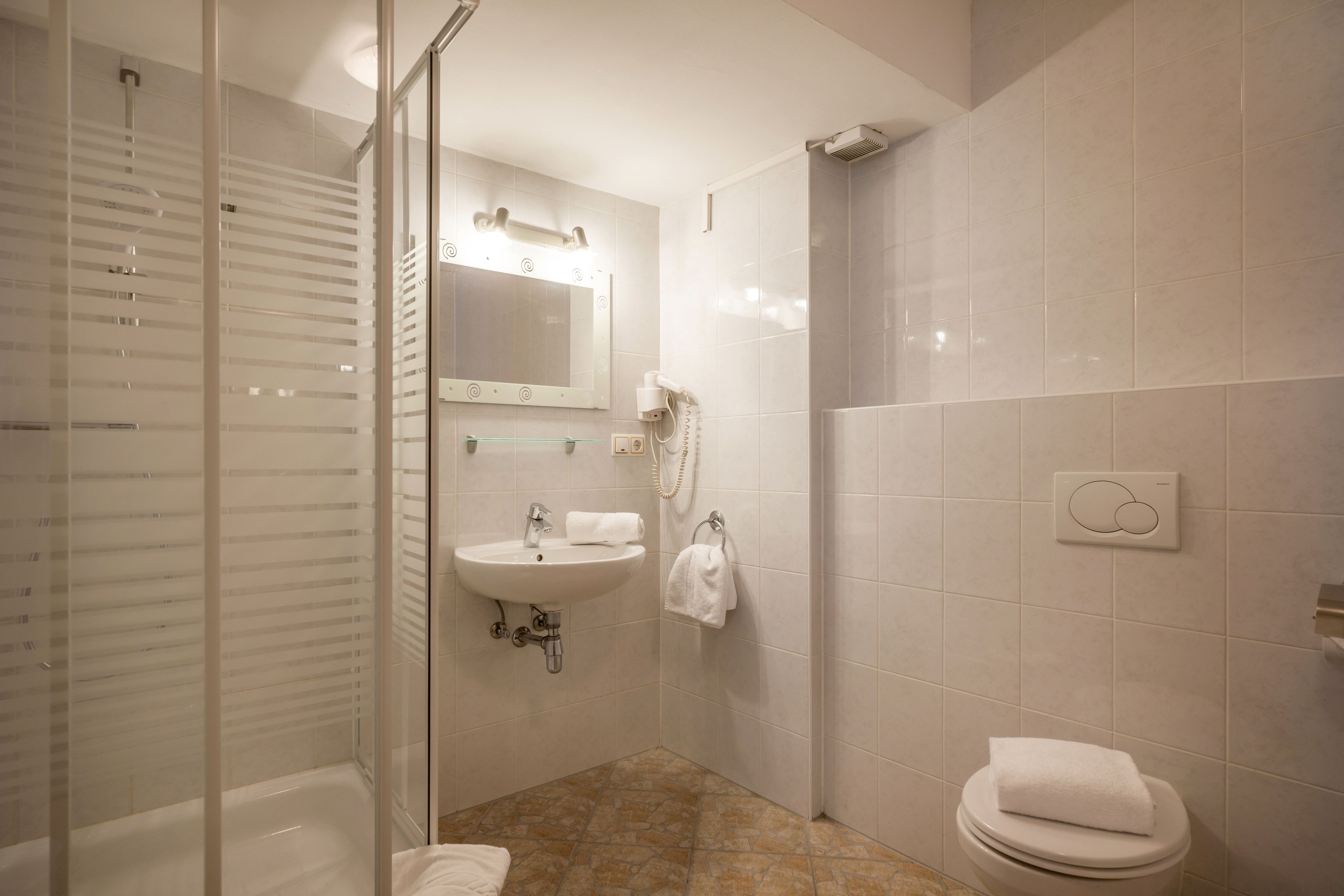 A modern bathroom with a glass shower enclosure, a sink, and a toilet.