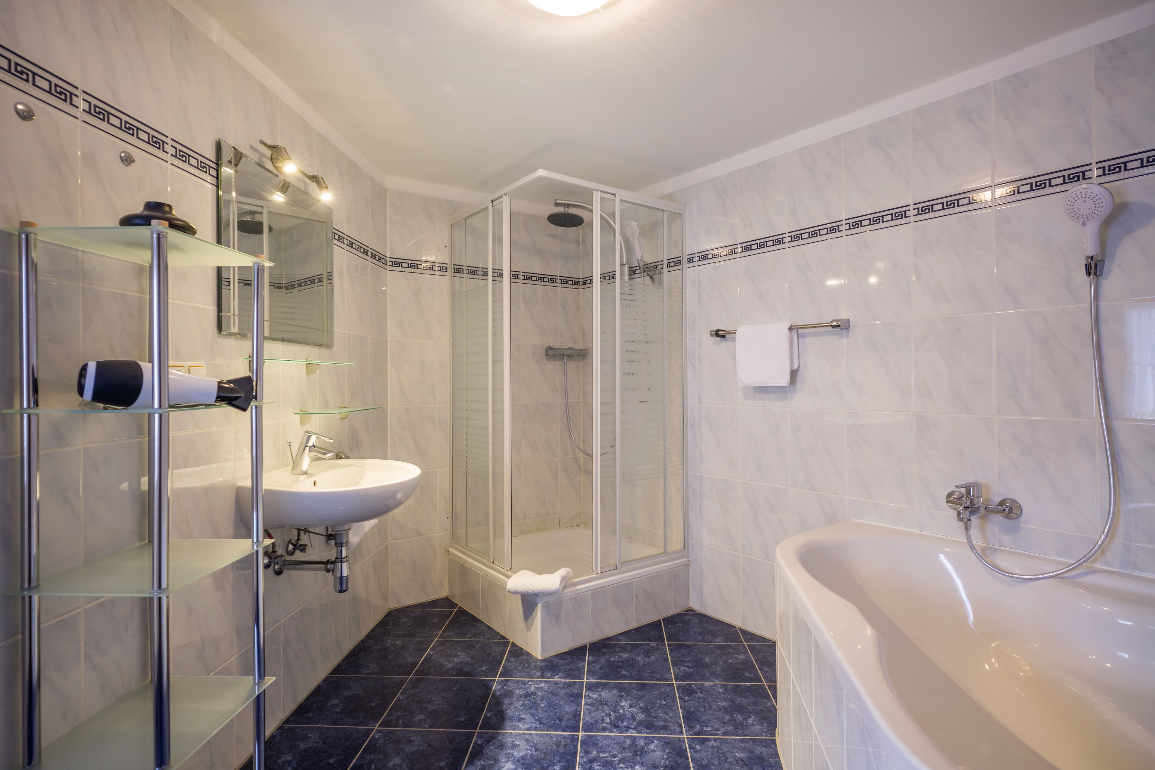 Ein modernes Badezimmer mit einer gläsernen Duschkabine, einem weißen Waschbecken und einer freistehenden Badewanne.