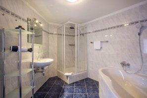 A modern bathroom with a glass-enclosed shower, a white sink, and a freestanding bathtub. - Familienparadies MoNi (Thiersee)