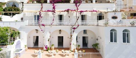 A multi-story building with white walls, arched doorways, and balconies with white railings.