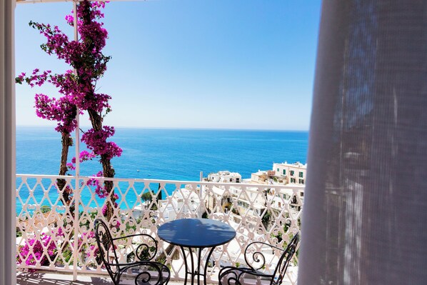 A balcony with a table and chairs, overlooking a coastal view with buildings and the sea. - La Bizantina (Positano)