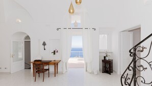 Une pièce spacieuse avec vue sur la mer, un coin repas comprenant une table et des chaises, et un escalier agrémenté de rampes décoratives.