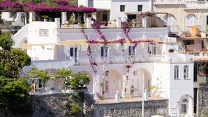 Un bâtiment situé sur la côte, doté de façades blanches, de balcons et d’arcades.