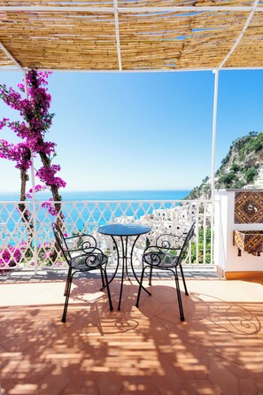 A terrace with a table and chairs, overlooking a coastal view. - La Bizantina (Positano)