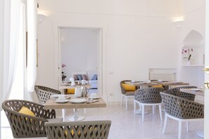 A modern dining area with wicker chairs and a wooden table set for four. - La Bizantina (Positano)