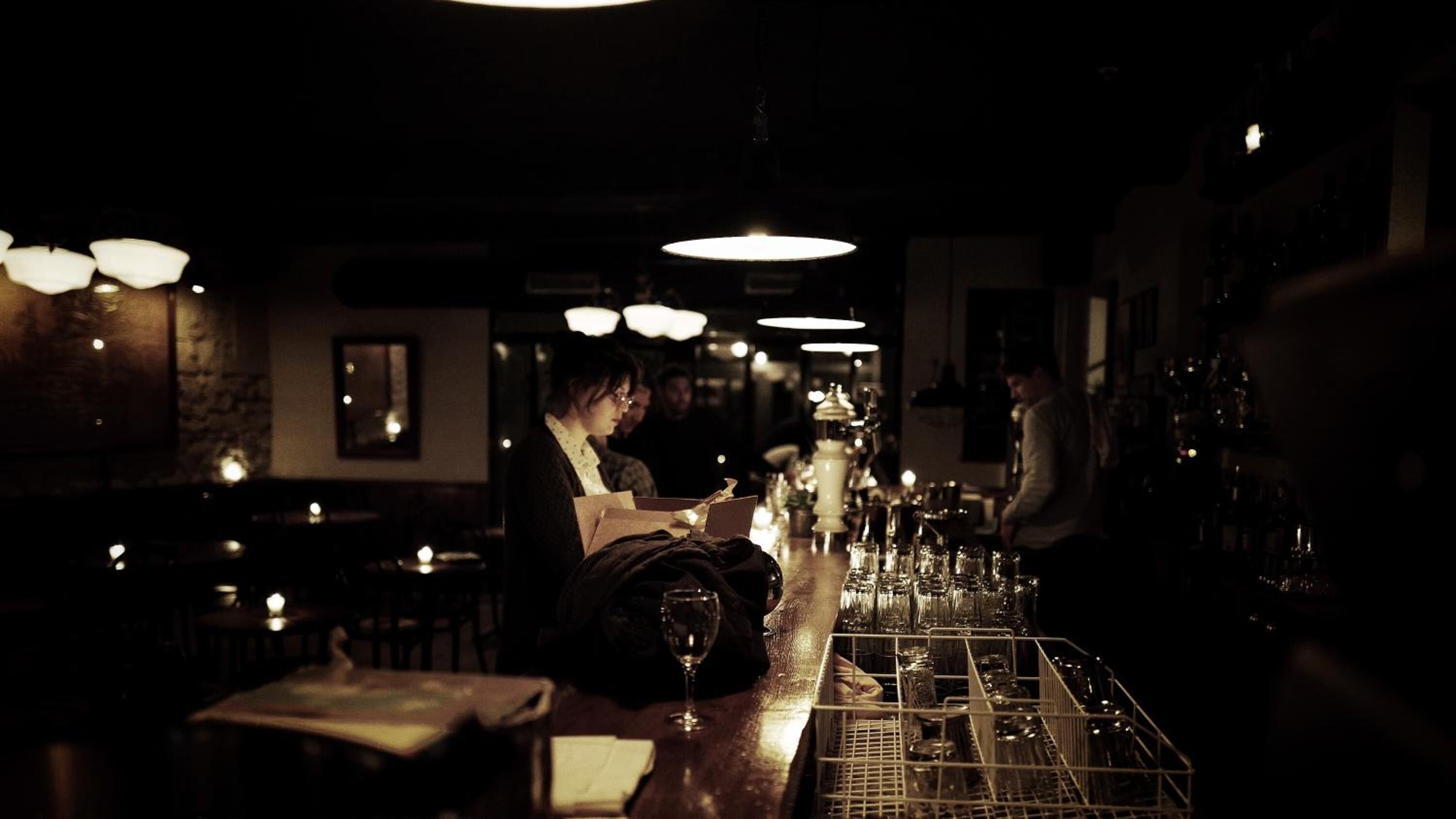 A dimly lit bar area with a bartender preparing drinks.