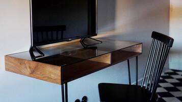 A modern room with a wooden desk, a black chair, a large flat-screen TV, and a checkered floor.