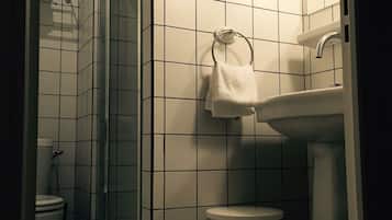 Un baño con azulejos blancos, un lavabo, un inodoro y una zona de ducha.