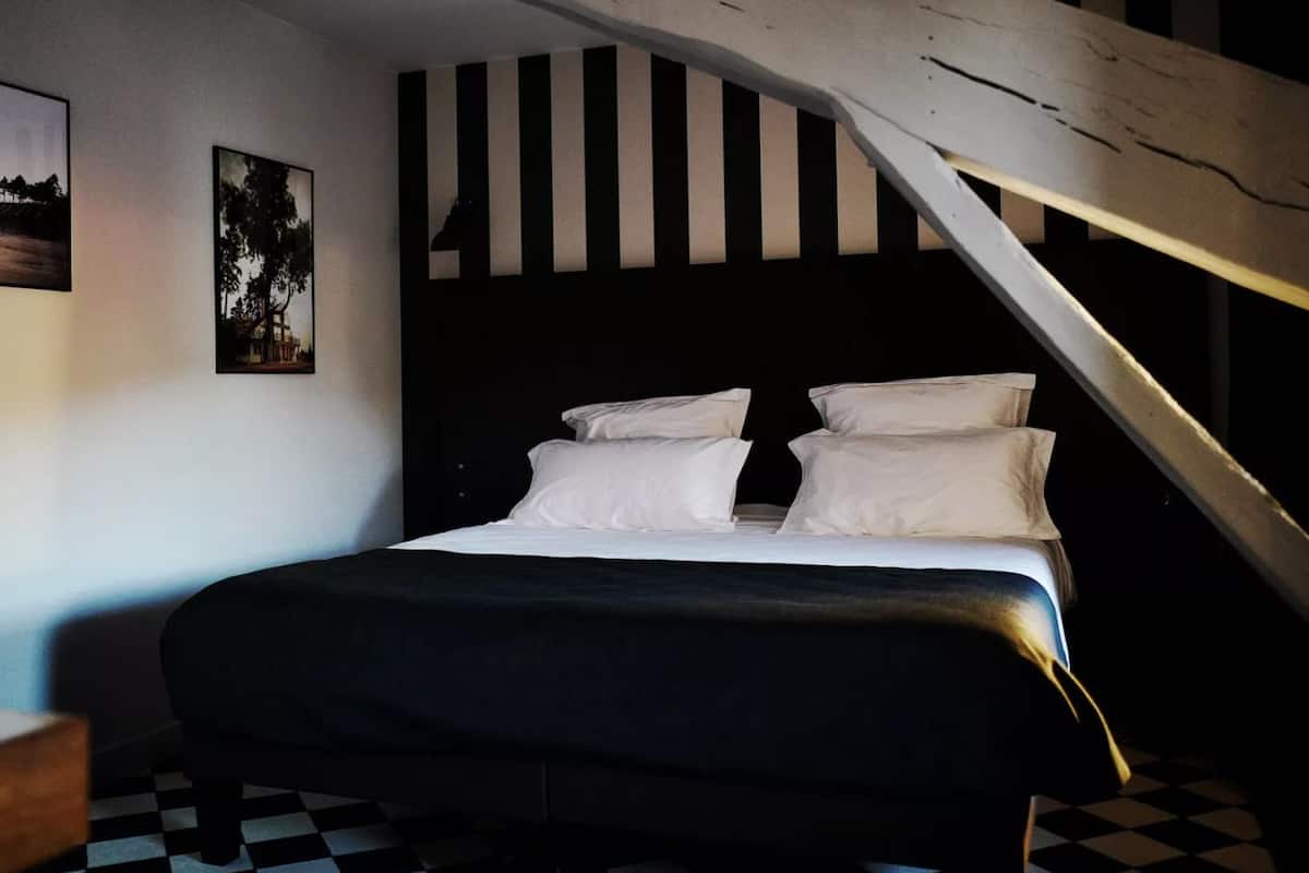 Une chambre à coucher avec un lit, un mur à rayures noires et blanches et un sol à carreaux.
