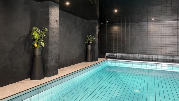 Una piscina interior con paredes negras y suelo de baldosas.