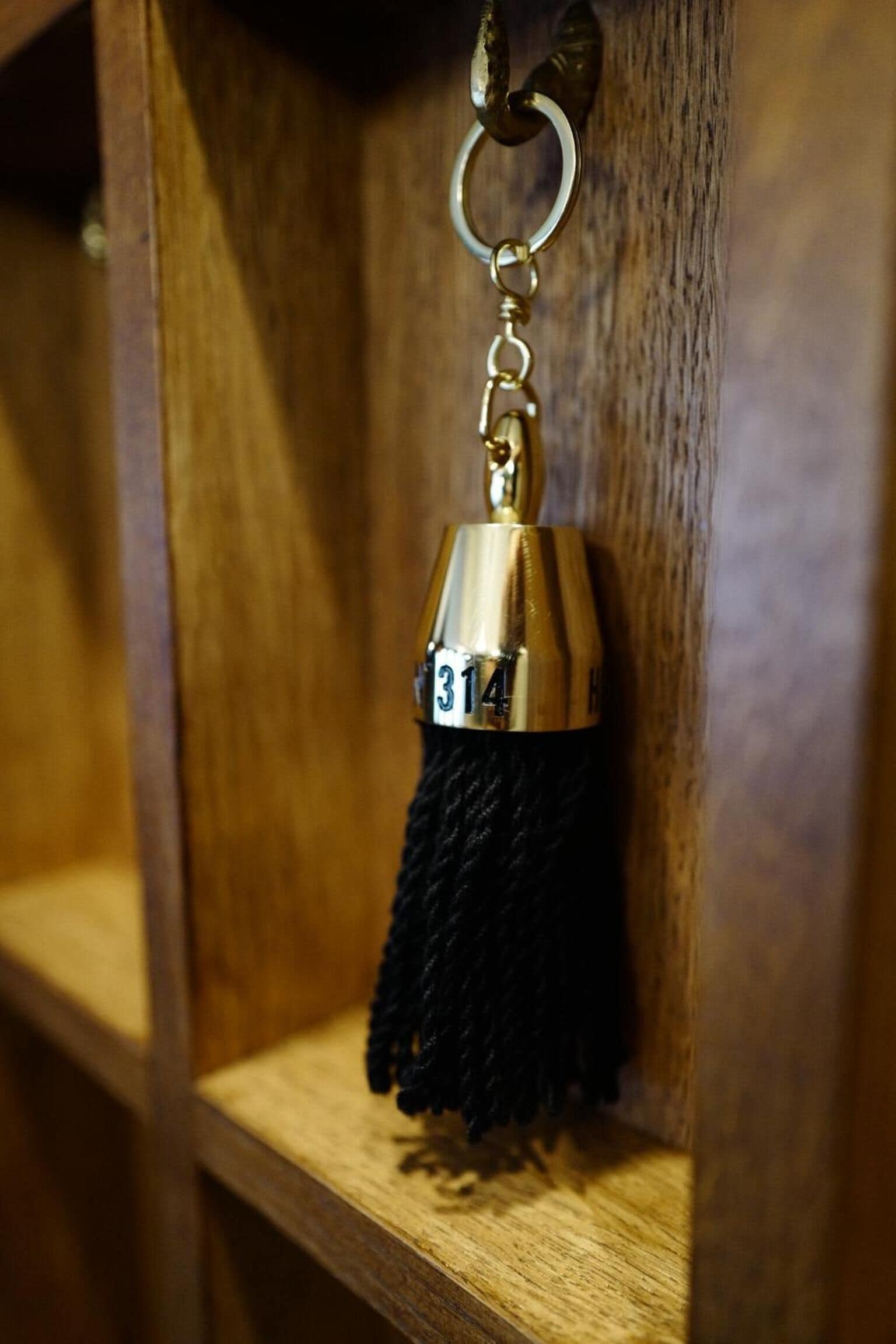 A wooden shelf with a metal keychain hanging from it.