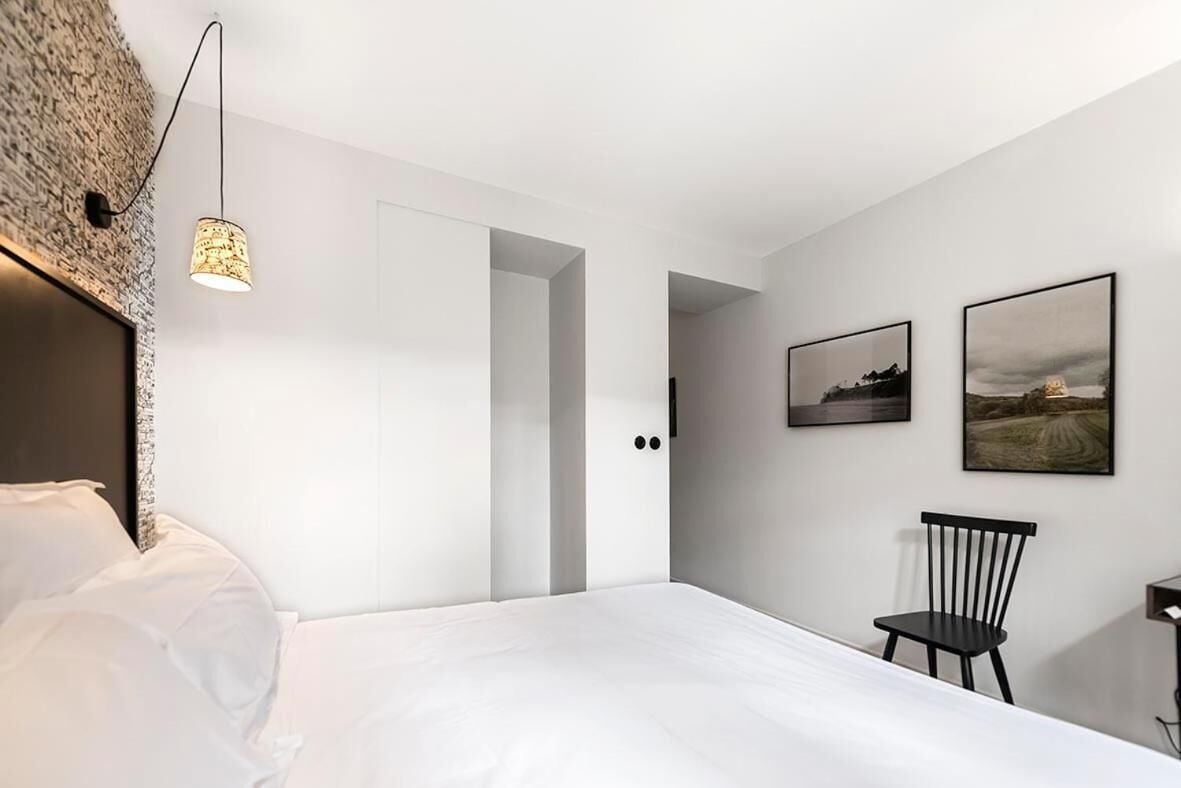 A modern bedroom with a bed, a chair, and two framed pictures on the wall.