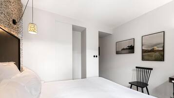A modern bedroom with a bed, a chair, and two framed pictures on the wall.
