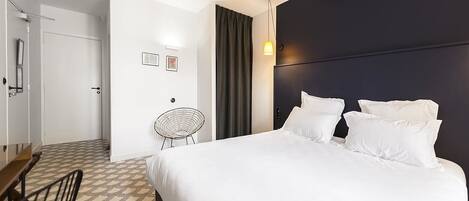 A hotel room with a large bed, a desk, and a chair.
