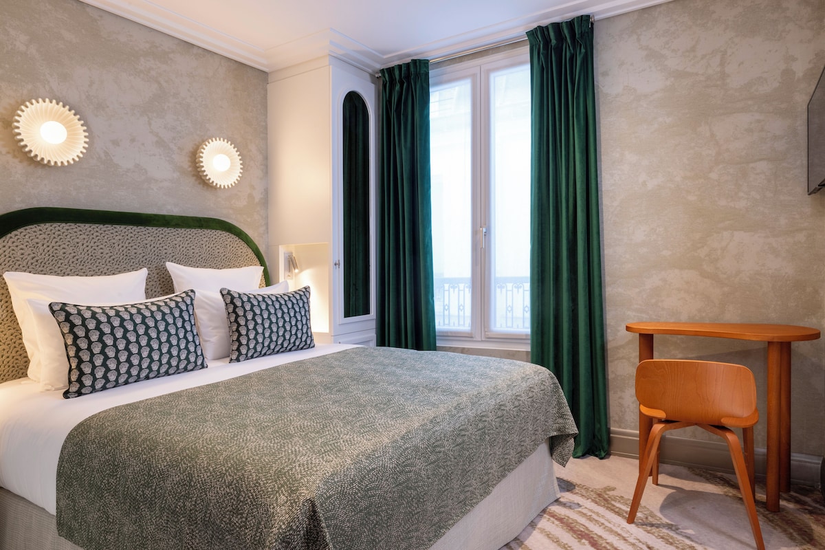 Un dormitorio ordenado con una cama grande, una silla de madera y una ventana con cortinas.