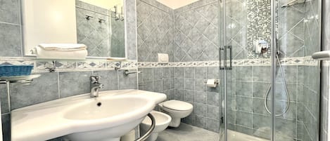 A modern bathroom with a sink, toilet, and glass-enclosed shower.