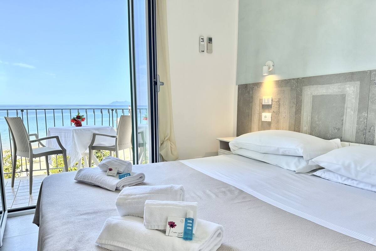 Una habitación de hotel con cama, una mesita con sillas y vista al mar.