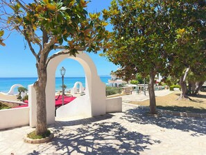 A paved pathway with an archway leading to a view of the sea.