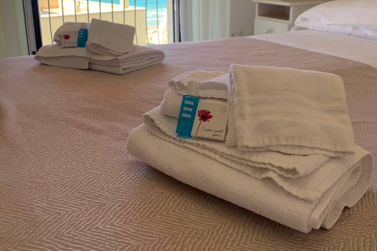 Habitación de hotel con cama, mesita de noche y vista a la playa.