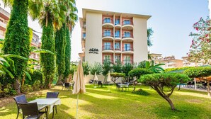 Ein Hotel mit Garten und einer Terrassenbereits mit Sitzgelegenheiten und Sonnenschirmen.