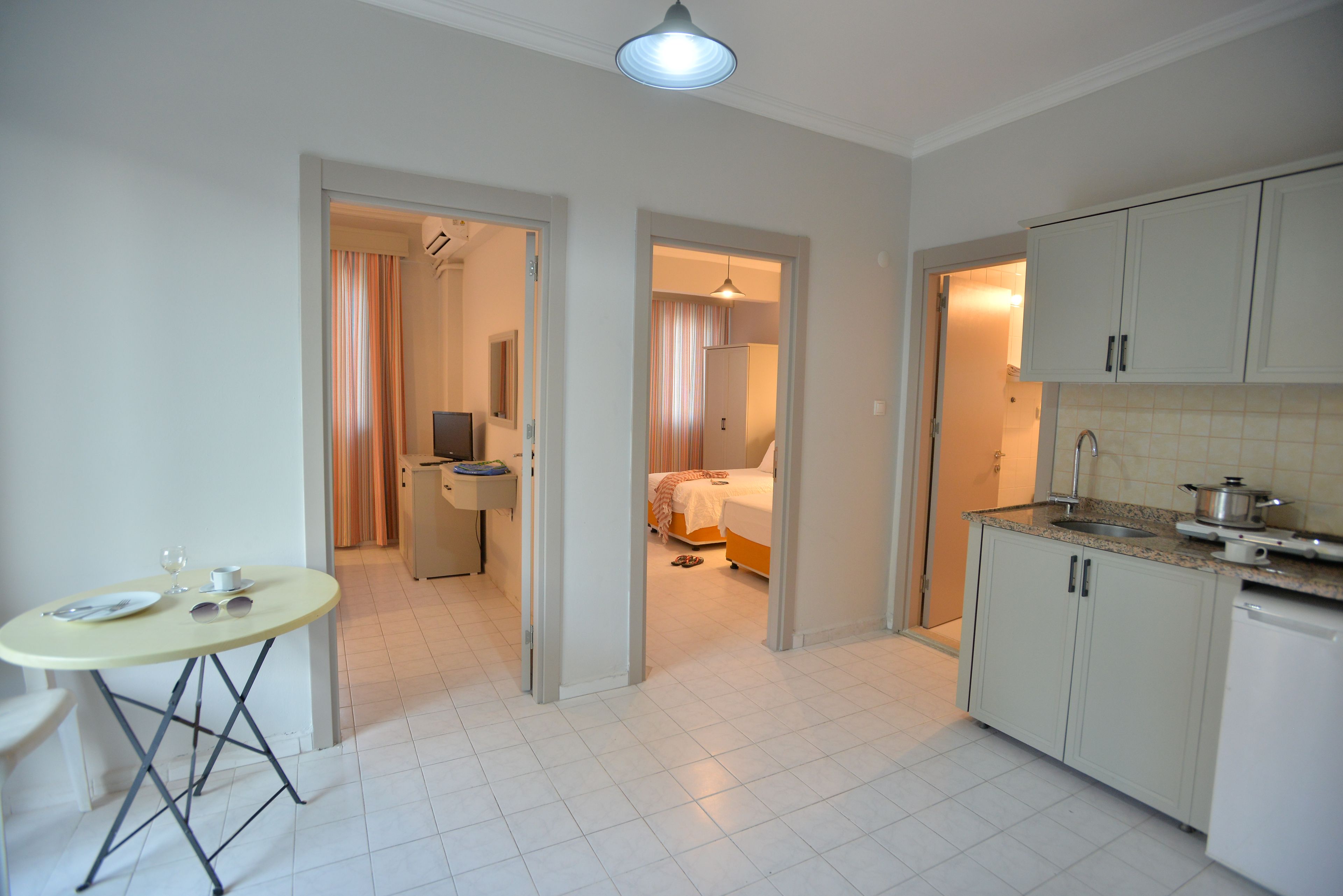 A compact hotel room with a kitchenette, a dining area, and a bathroom.