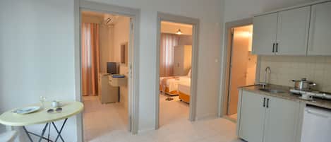 A compact hotel room with a kitchenette, a dining area, and a bathroom.