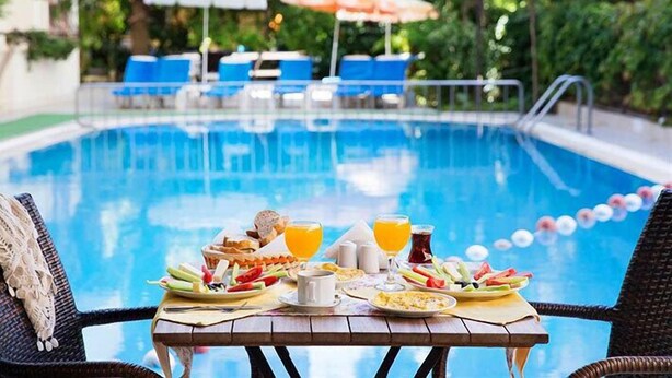 Frühstück am Pool mit Tisch, Stühlen und Pool im Hintergrund.