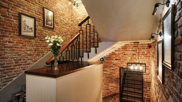 A staircase with a brick wall, wooden handrail, and a vase of white flowers.