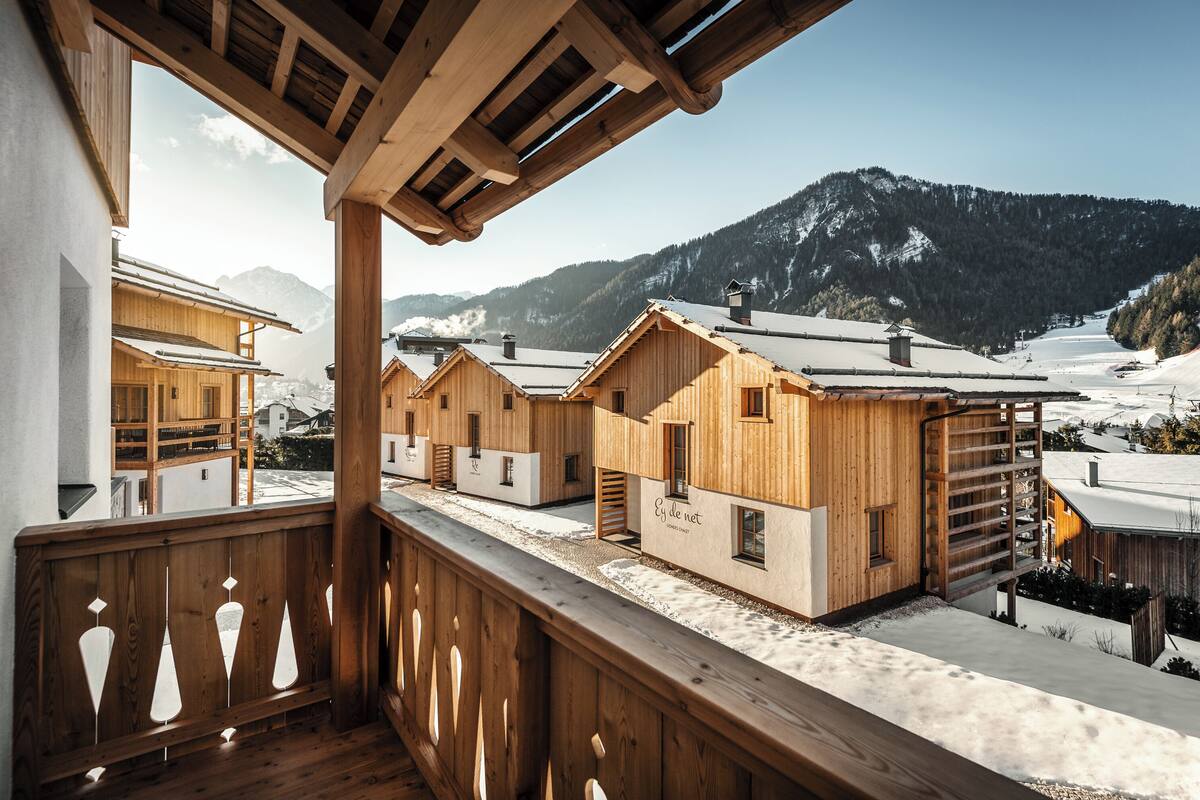 Un chalet en bois doté d’un balcon donnant sur un paysage montagneux enneigé.
