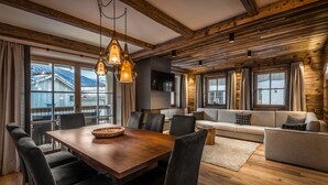 Een houten interieur met een eettafel, stoelen, een bank en een televisie.