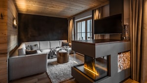 Een moderne woonkamer met een open haard, een bank en een televisie.