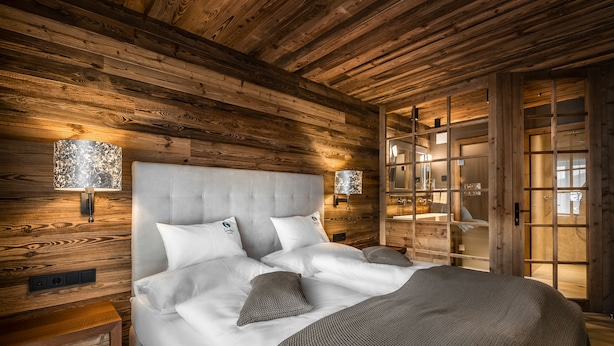 Een slaapkamer met houten lambrisering, een groot bed, twee bedlampen en een nachtkastje van hout.