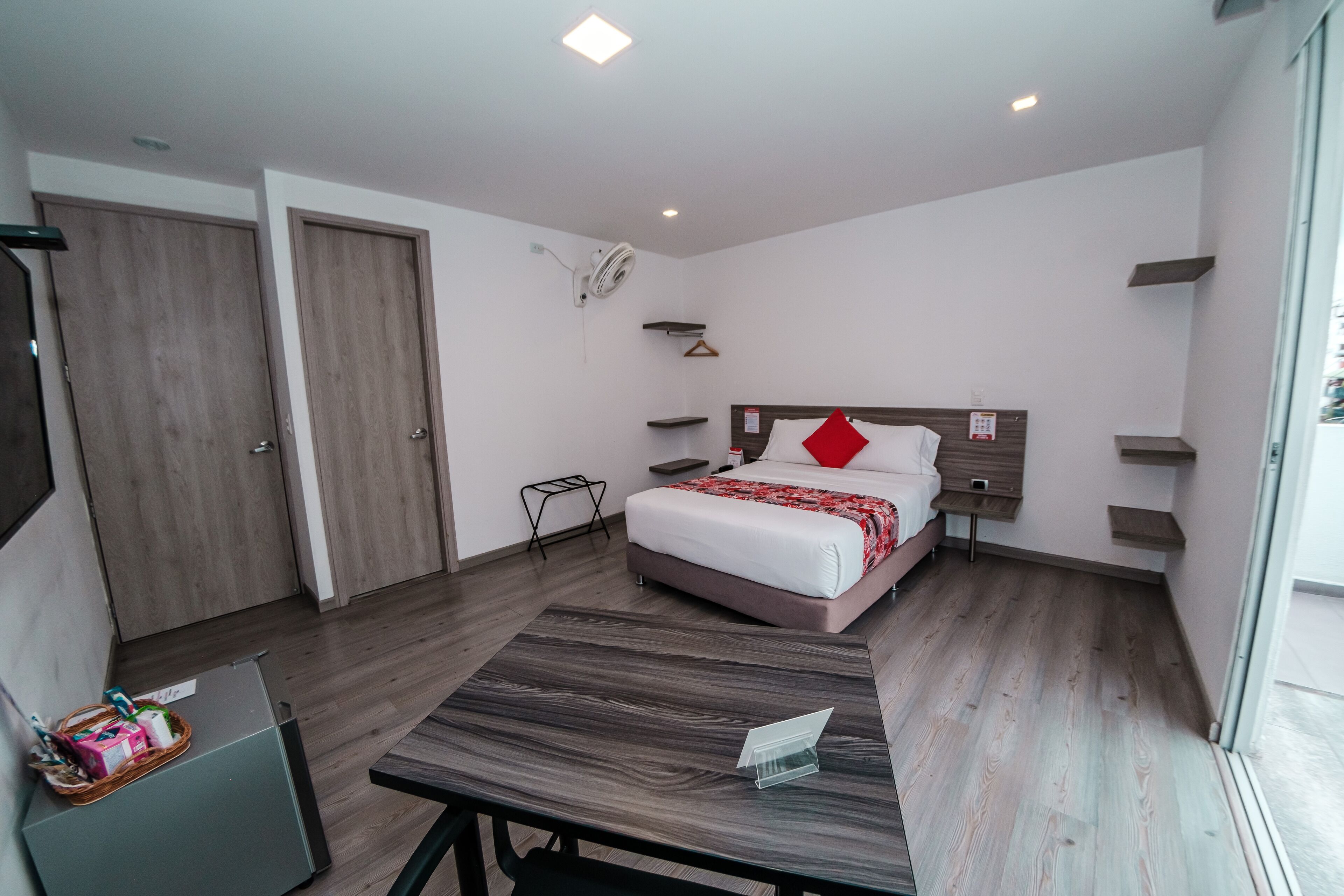 Una habitación de hotel moderna con cama, mesitas de noche, escritorio y armario.