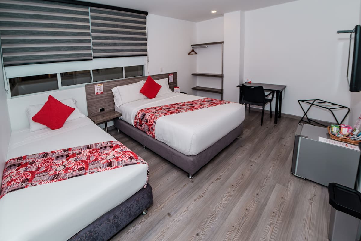 A hotel room with two beds, a desk, and a chair.