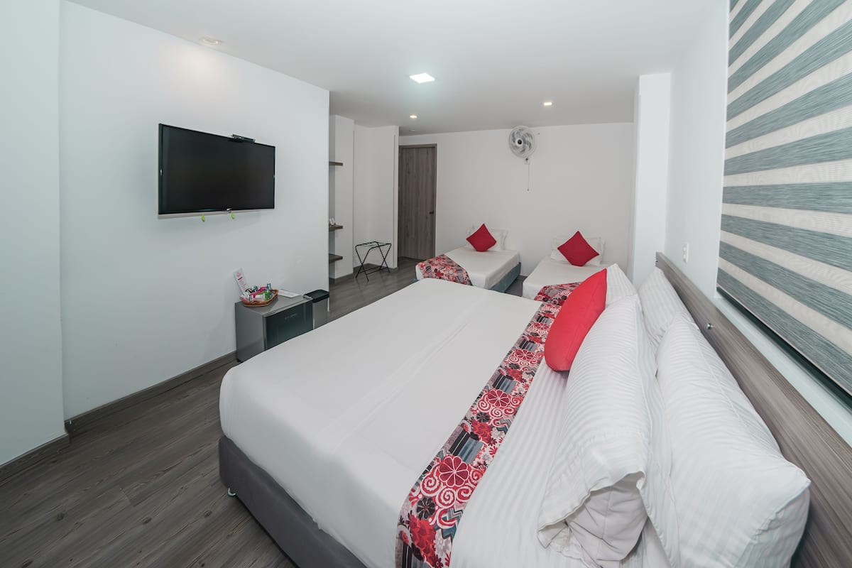 A modern hotel room with a large bed, a flat-screen TV, and a fan.