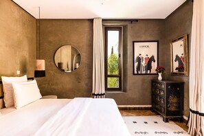 A bedroom with a large bed, a round mirror, a dresser, and a window with curtains. - Villa avec piscine privée et Golf (Marrakech)