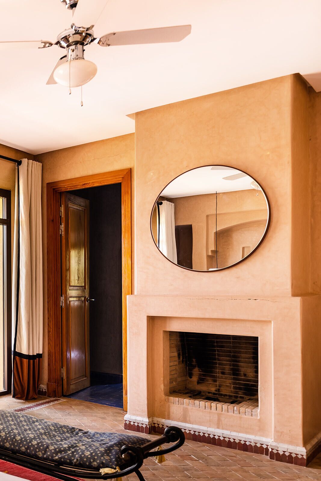 A room with a fireplace, a ceiling fan, and a mirror above it.