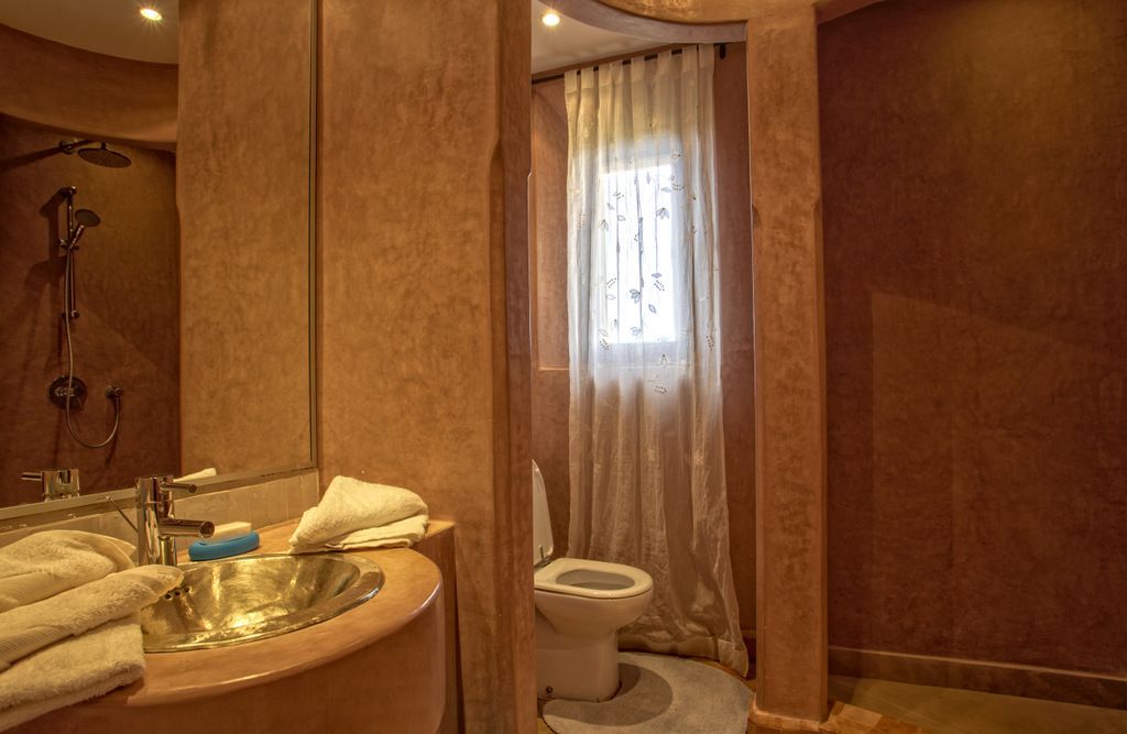 A bathroom with a sink, mirror, shower, and toilet.